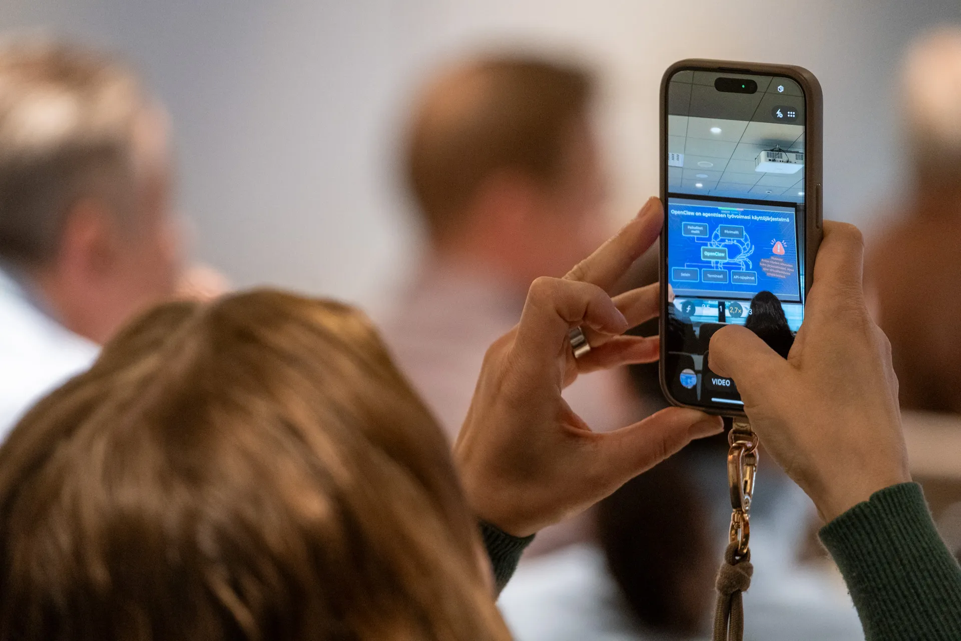 An event participant photographing an AI agent workflow slide during an AI-Keynote talk